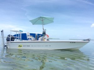 Keys Boat Tours motor boat at anchor with paddleboards and light blu umbrella